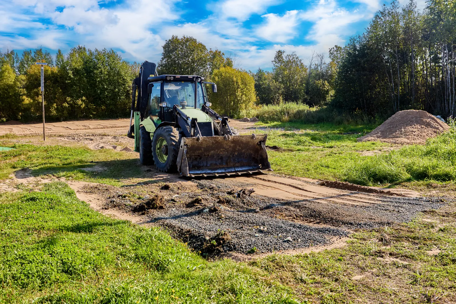 Backhoe loader grading and leveling ground during site preparation near Shelbyville, Indiana