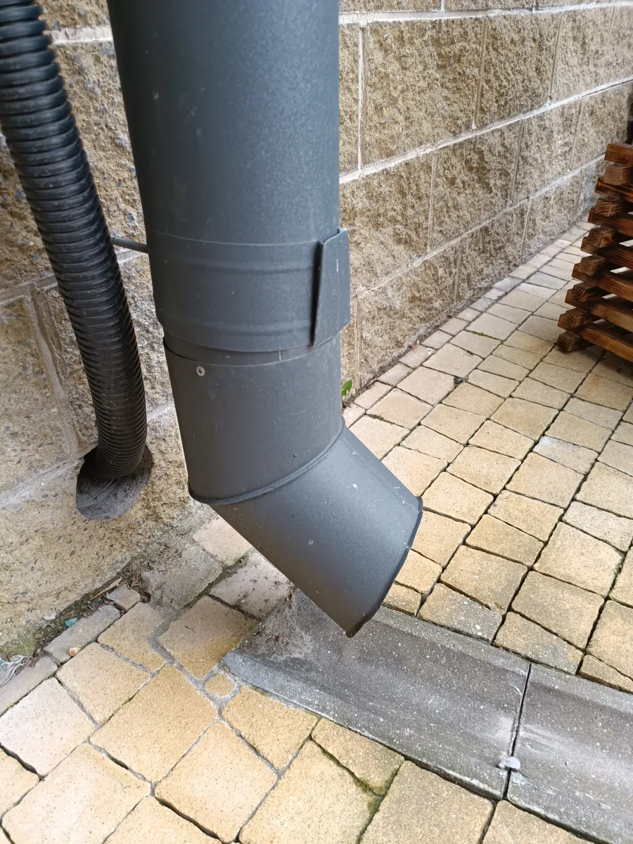Downspout and drainage pipe routing water away from a building foundation in central Indiana