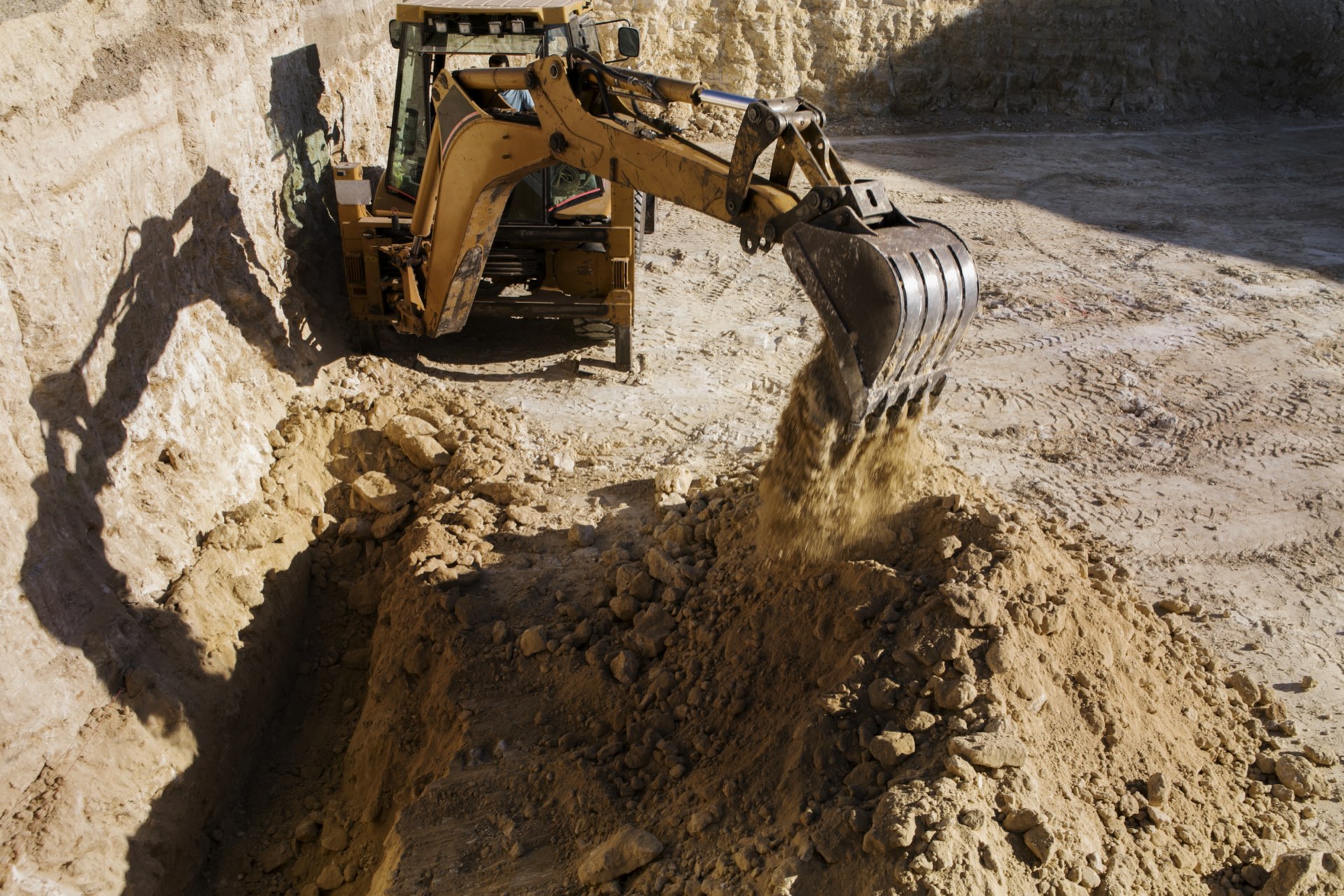 Excavator and skid steer grading a rural gravel driveway in central Indiana