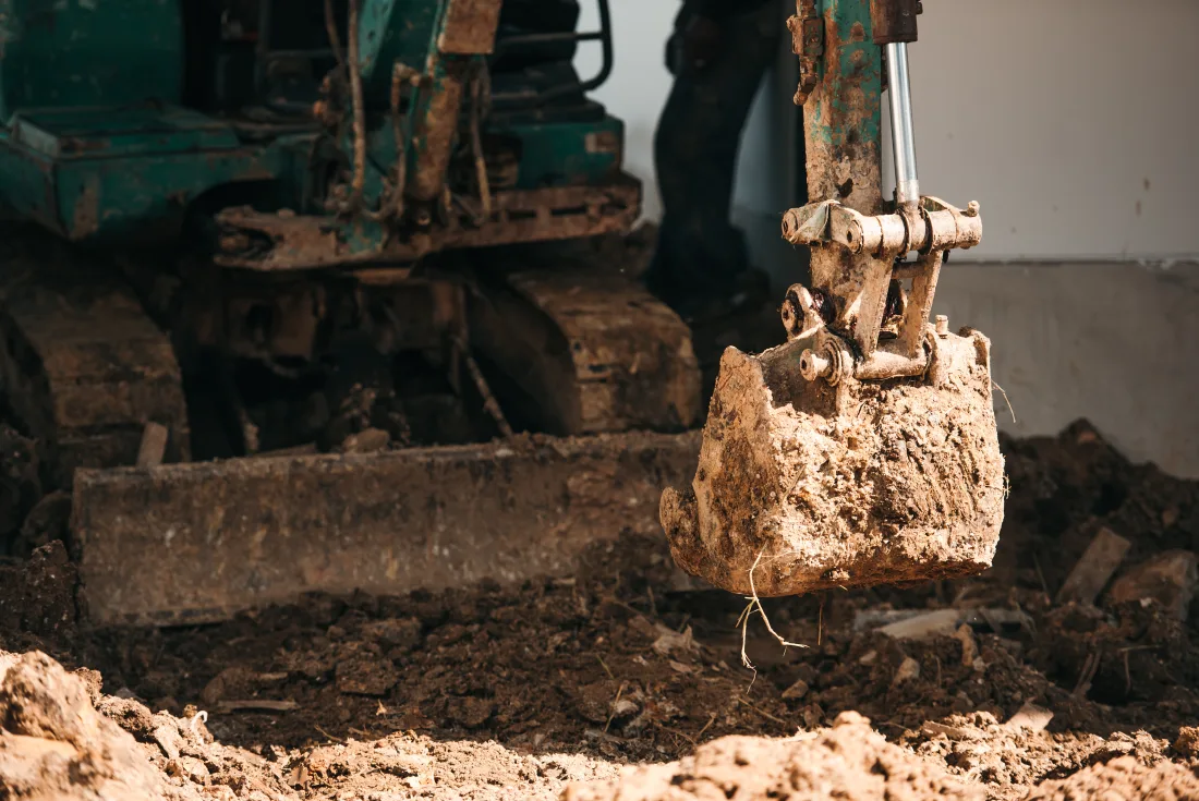 Mini excavator bucket digging and grading soil during site preparation in Shelby County, Indiana