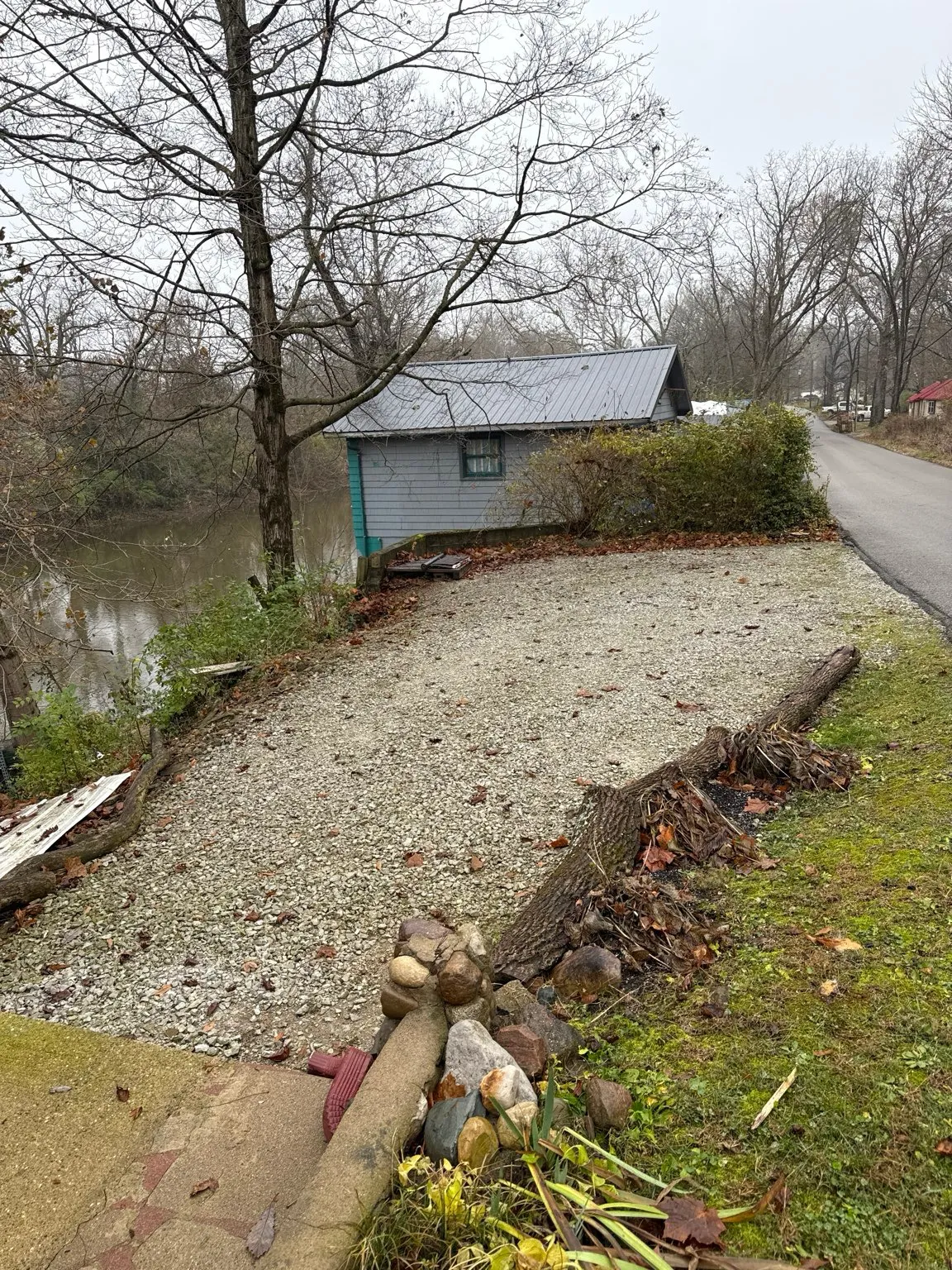 Finished gravel driveway curving past a lakeside shed after retaining wall work in central Indiana (photo 1)