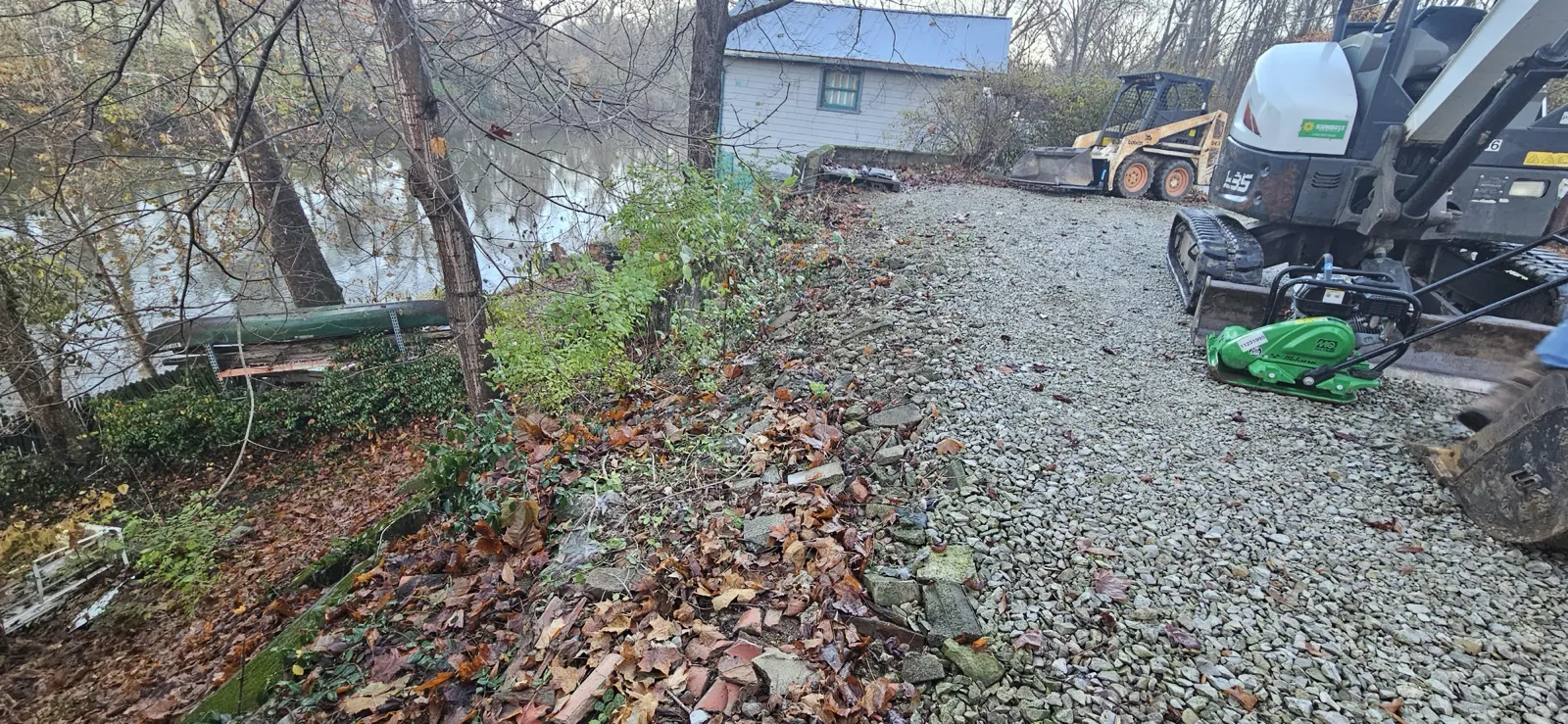 Excavator on a fresh gravel pad beside the water during a retaining wall project in central Indiana (photo 4)