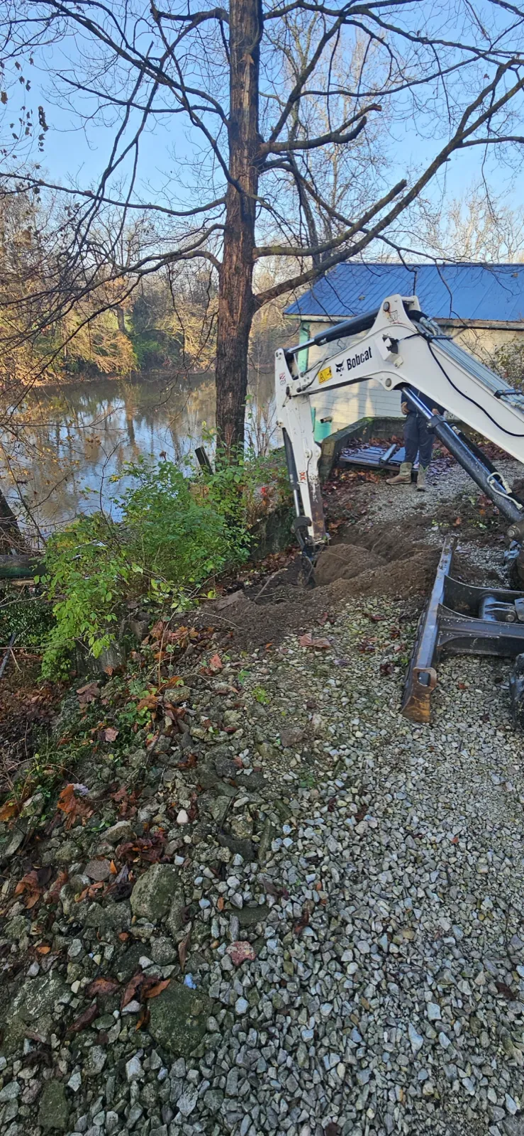 Skid steer grading gravel along the waterfront during retaining wall installation in central Indiana (photo 5)