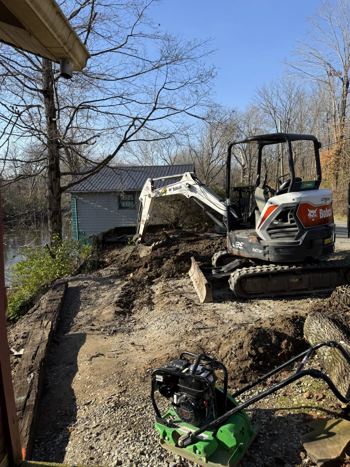 Excavator building up a slope beside a lakeside cabin in central Indiana (photo 6)