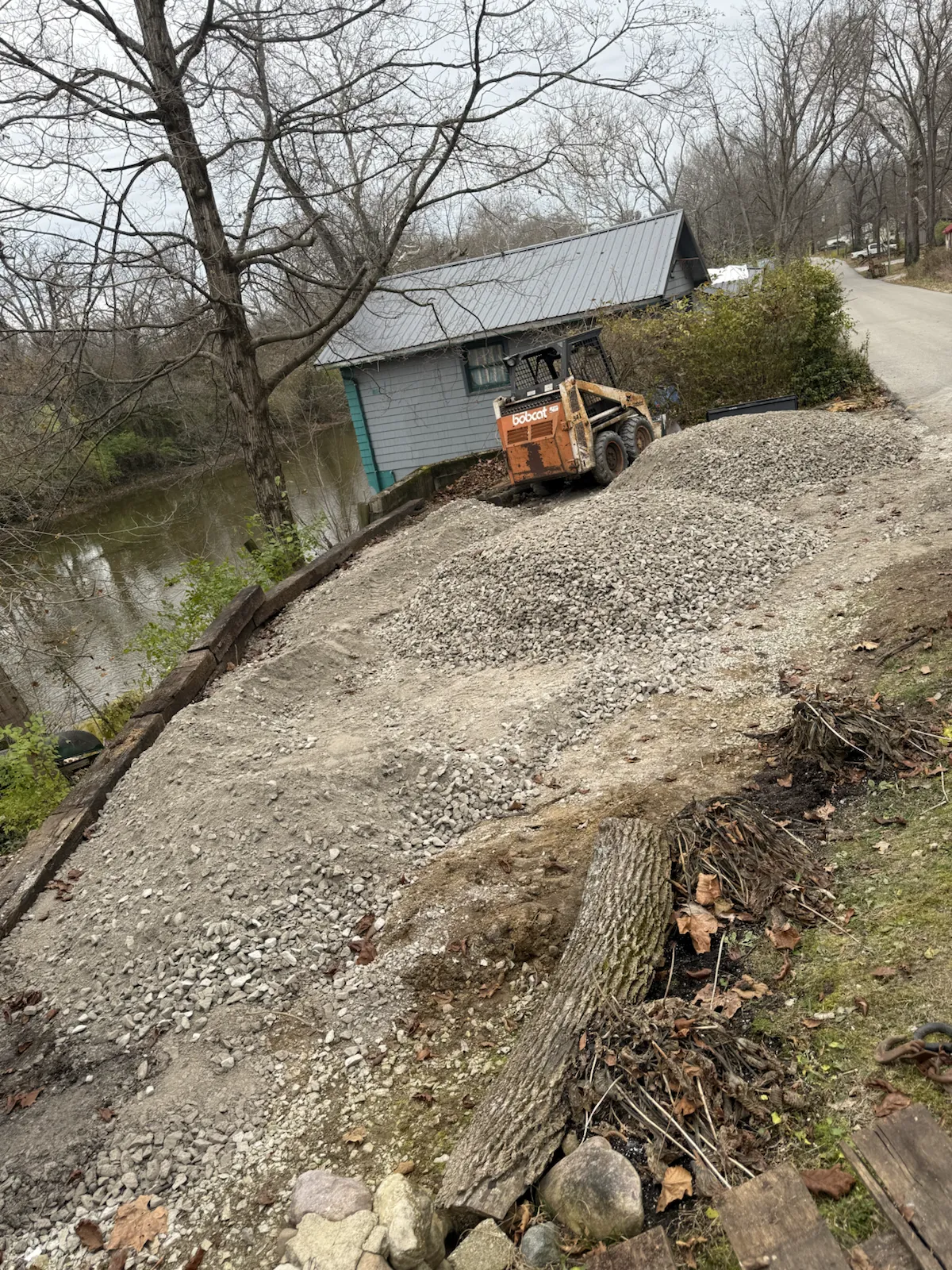 Skid steer stabilizing an eroded slope beside a red cabin in central Indiana (photo 7)
